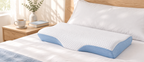 SleepCradle Contour Pillow on a bed beside a bedside table